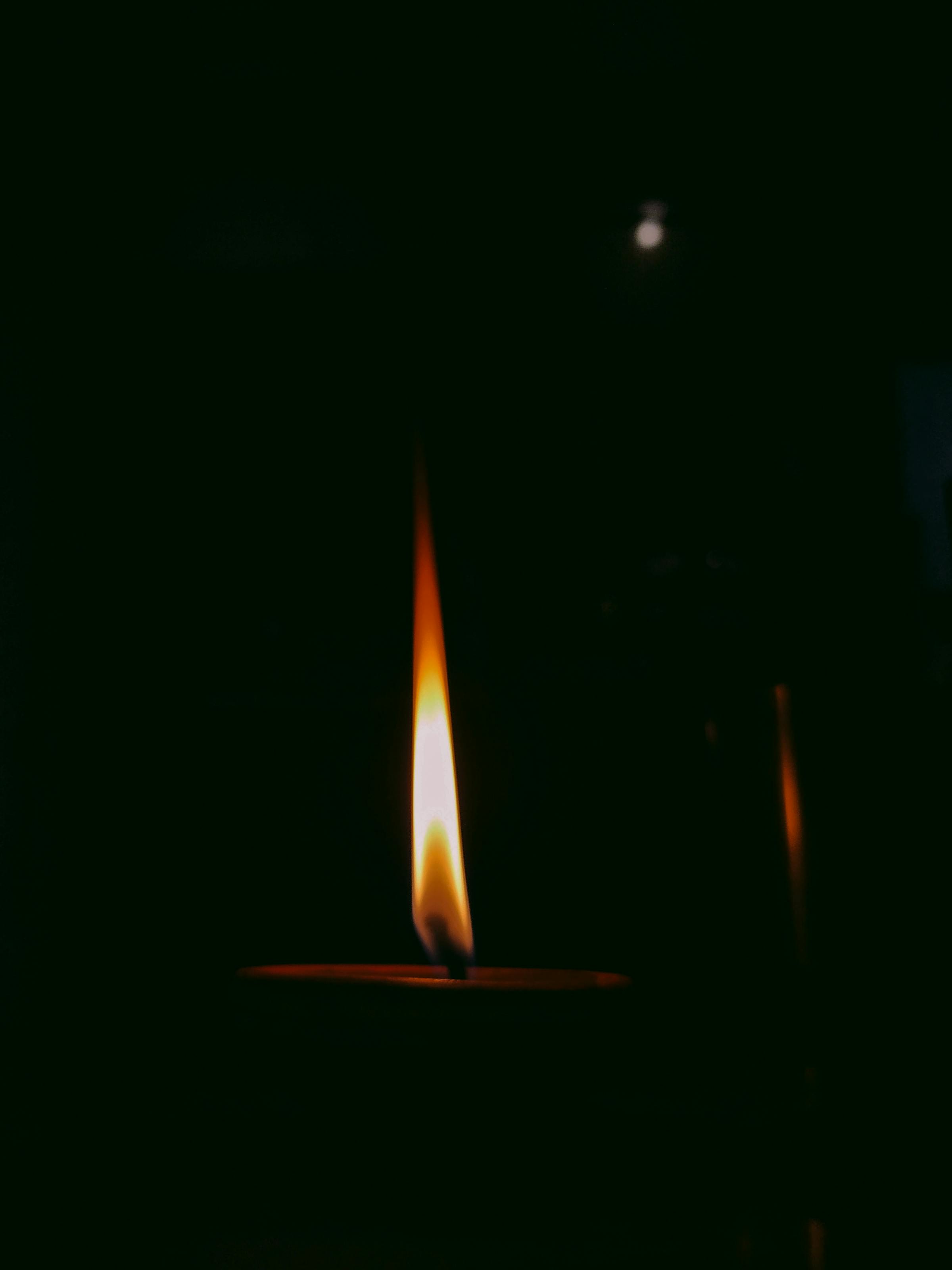 Eine einzelne Kerzenflamme in warmer Dunkelheit — ruhige, bewusste Zeit